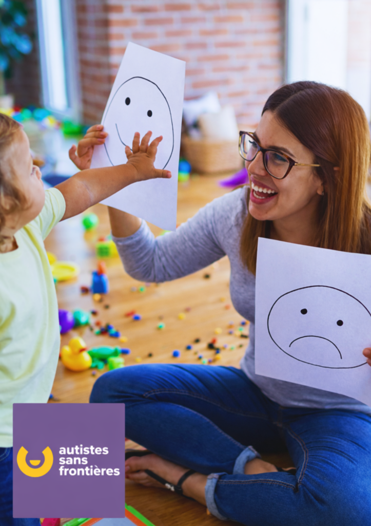 Une éducatrice souriante interagit avec un jeune enfant en utilisant des dessins d'expressions faciales, logo Autistes sans Frontières en incrustation.