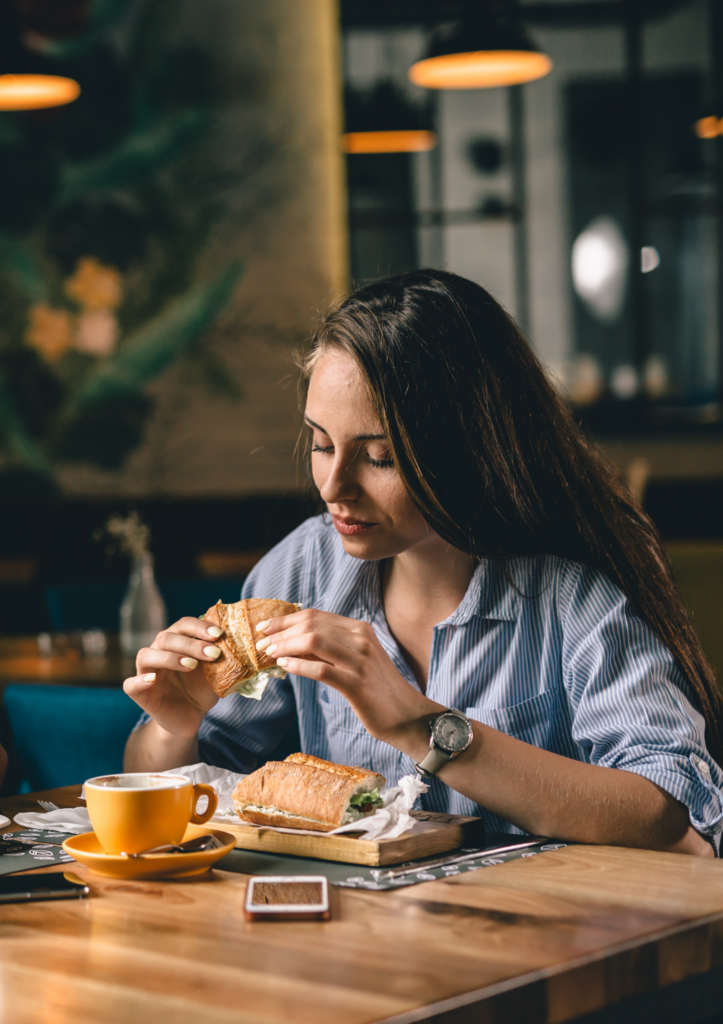 Jeune femme prenant son déjeuner dans un café, illustrant le quotidien des participants au programme 1 Table pour 4.