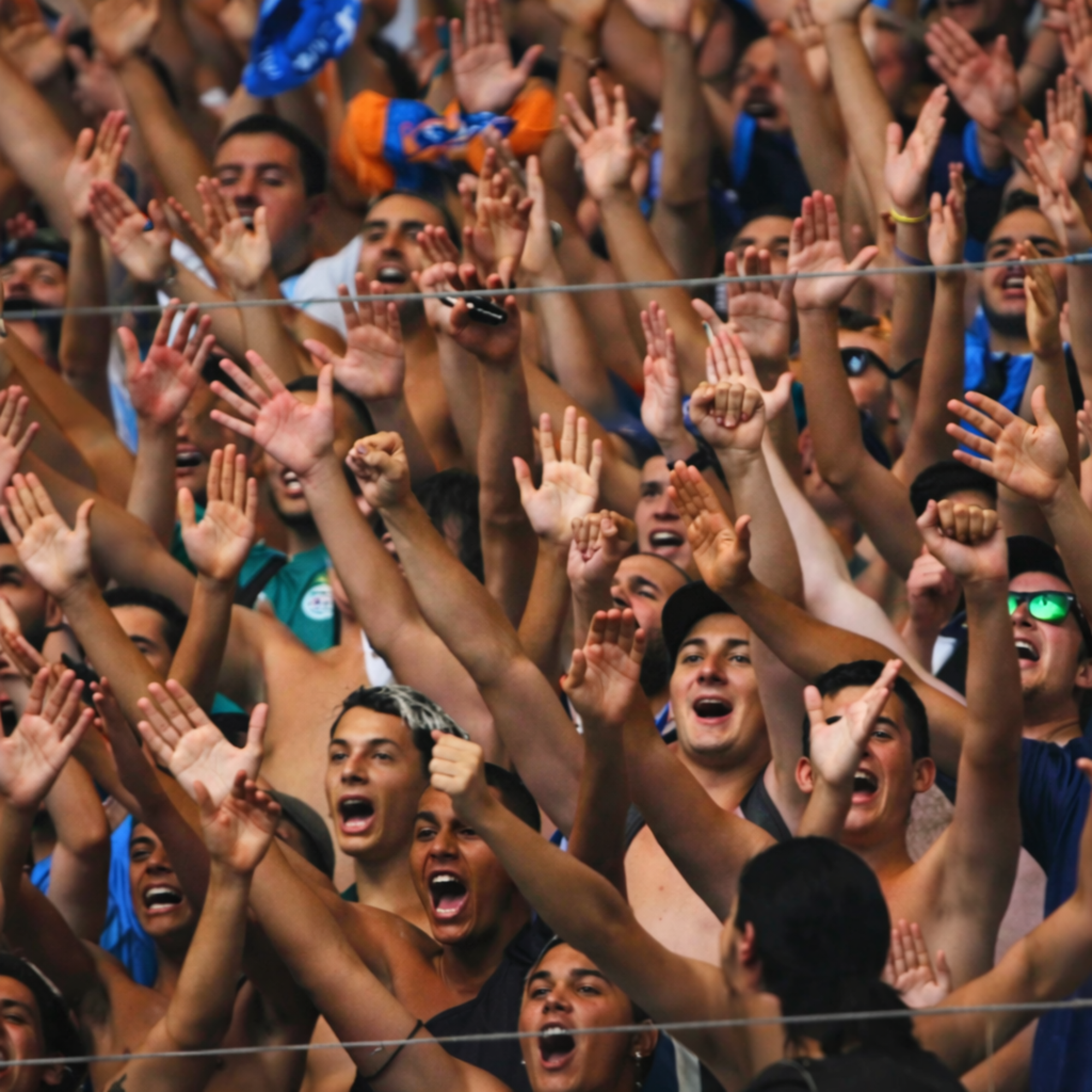 Foule de supporters enthousiastes dans les tribunes levant les mains en signe de soutien et de célébration lors d'un événement de l'association Big Impacts.